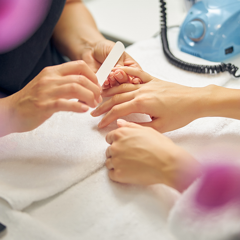 woman having nails filed by professional in salon